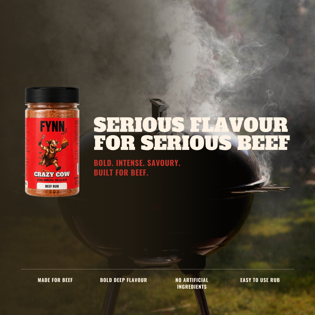A jar of Fynn. 'Crazy Cow' beef rub shown next to a black smoking grill with bold white and red text reading 'SERIOUS FLAVOUR FOR SERIOUS BEEF' on a dark, smoky outdoor background.