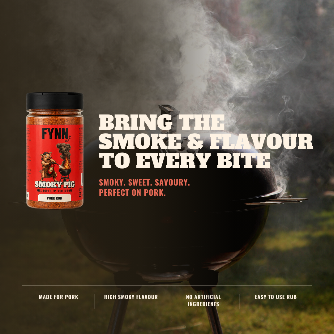 A jar of Fynn Smokey Pig rub shown next to a black kettle grill with smoke rising, on a dark outdoor background. Large text reads 'BRING THE SMOKE & FLAVOUR TO EVERY BITE' with smaller descriptive copy below.